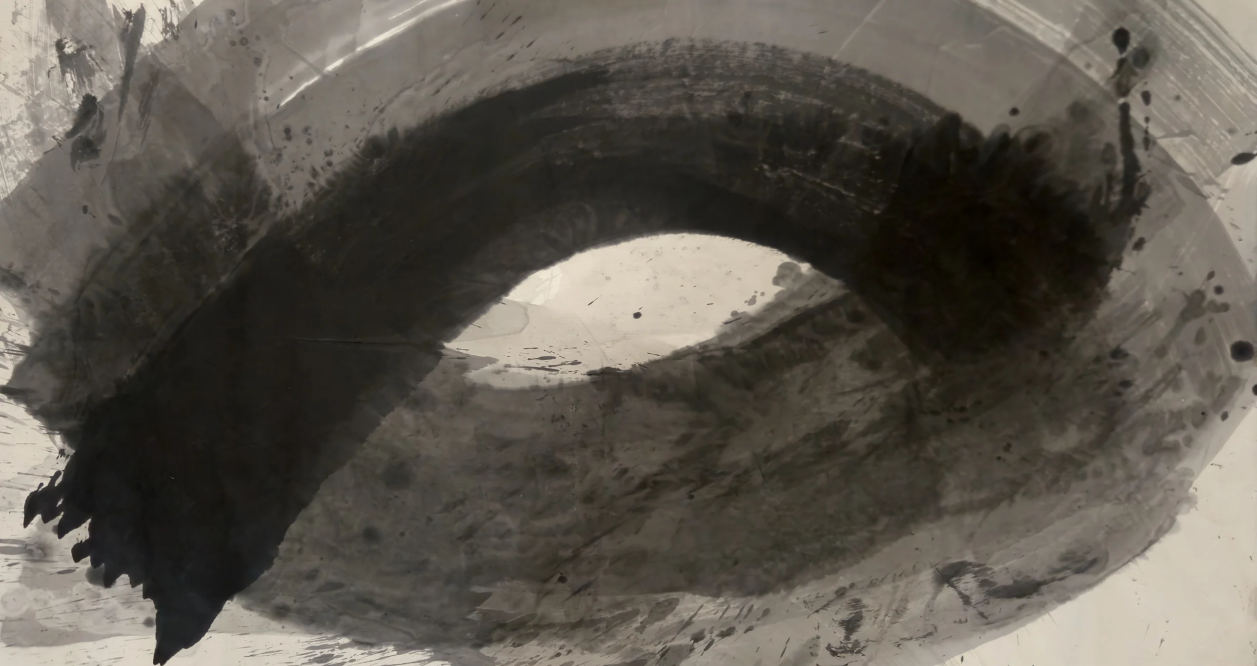 A huge dark ink loop sweeps across a beige sheet, black at lower left and upper right, enclosing a pale eye-shaped clearing at centre.
