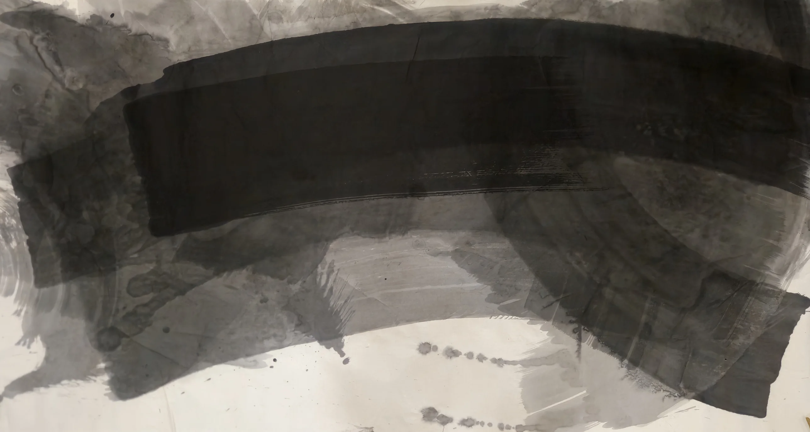 A broad black curved band crosses the upper half of a wide sheet, above a grey arc sweeping to lower right and white paper below.
