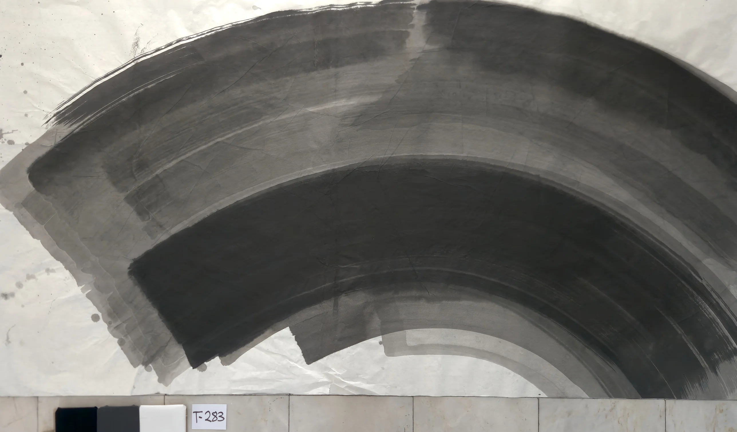 A broad grey and black arc sweeps from the left over the top to the bottom right corner, with bare paper at lower left.