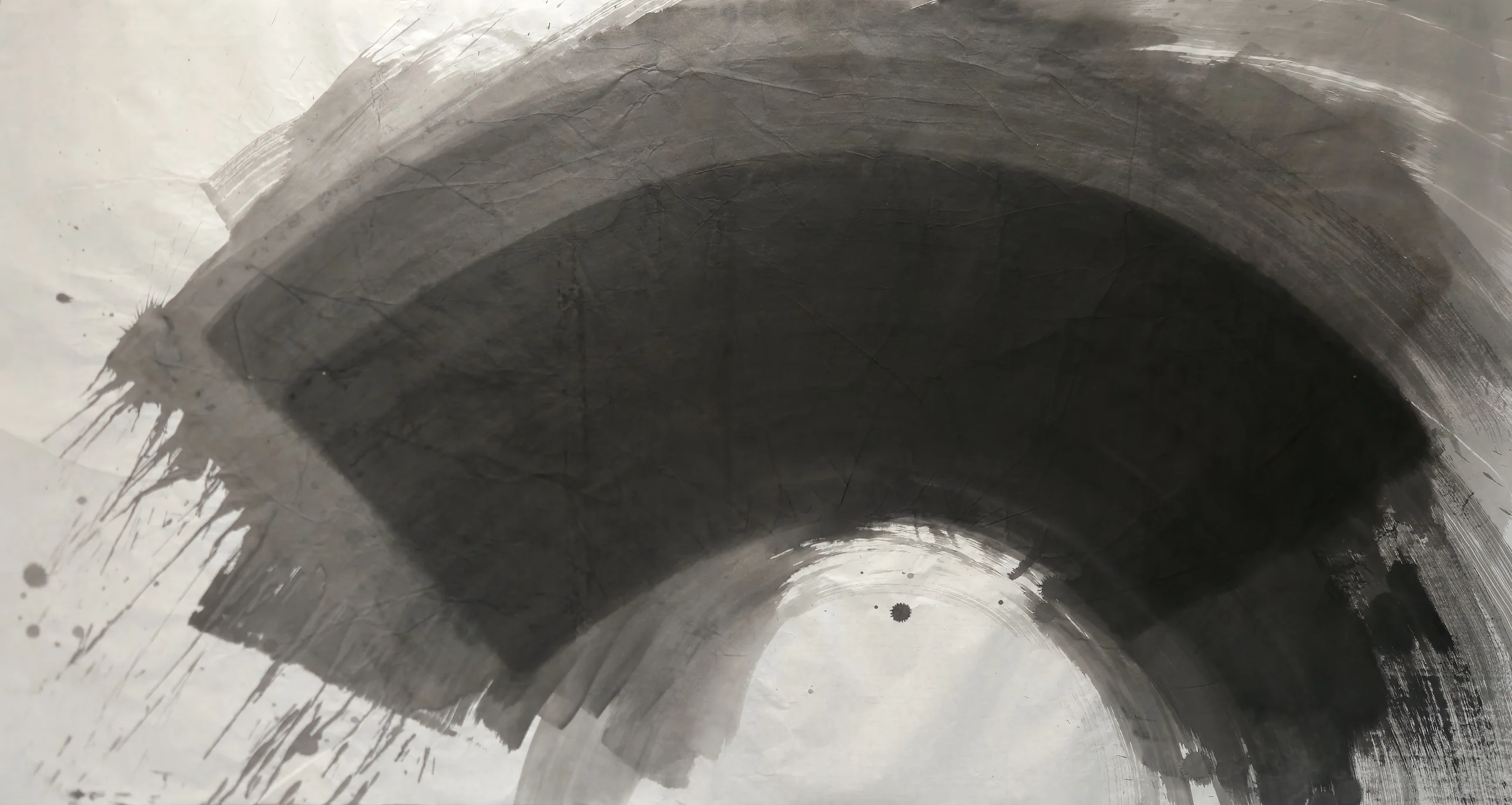 A large dark grey arch sweeps across pale paper, with drips at left, dry streaks at right, and a white dome-shaped space at bottom centre.