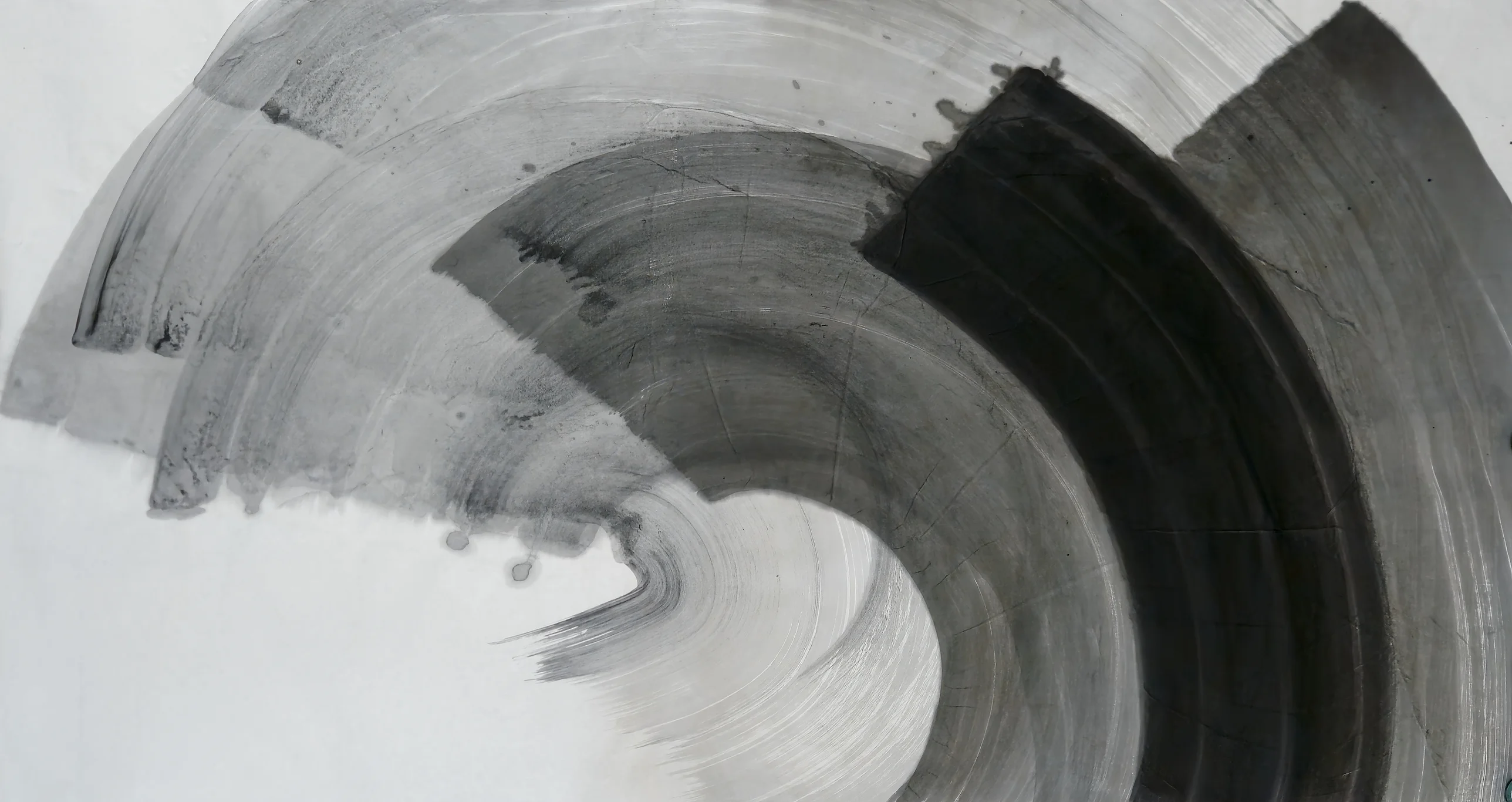 Wide grey and black brush arcs curve clockwise from pale upper left to a dark band at right, around white paper at lower left.