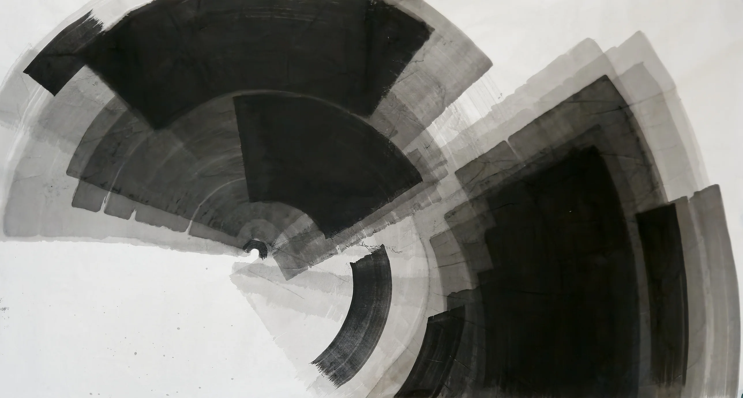 Two large fan shapes of black and grey ink radiate across white paper, upper left and lower right, with a curved dry stroke between.