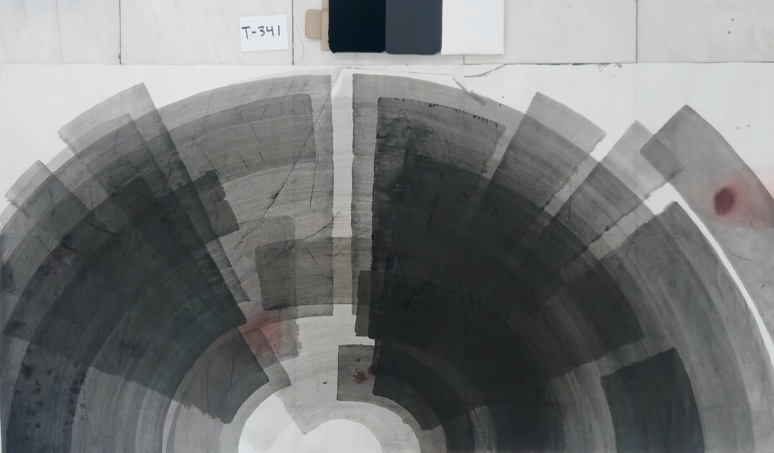 Grey and black bands form a half wheel round a white core at bottom centre, split by a pale vertical channel; red dot, upper right.
