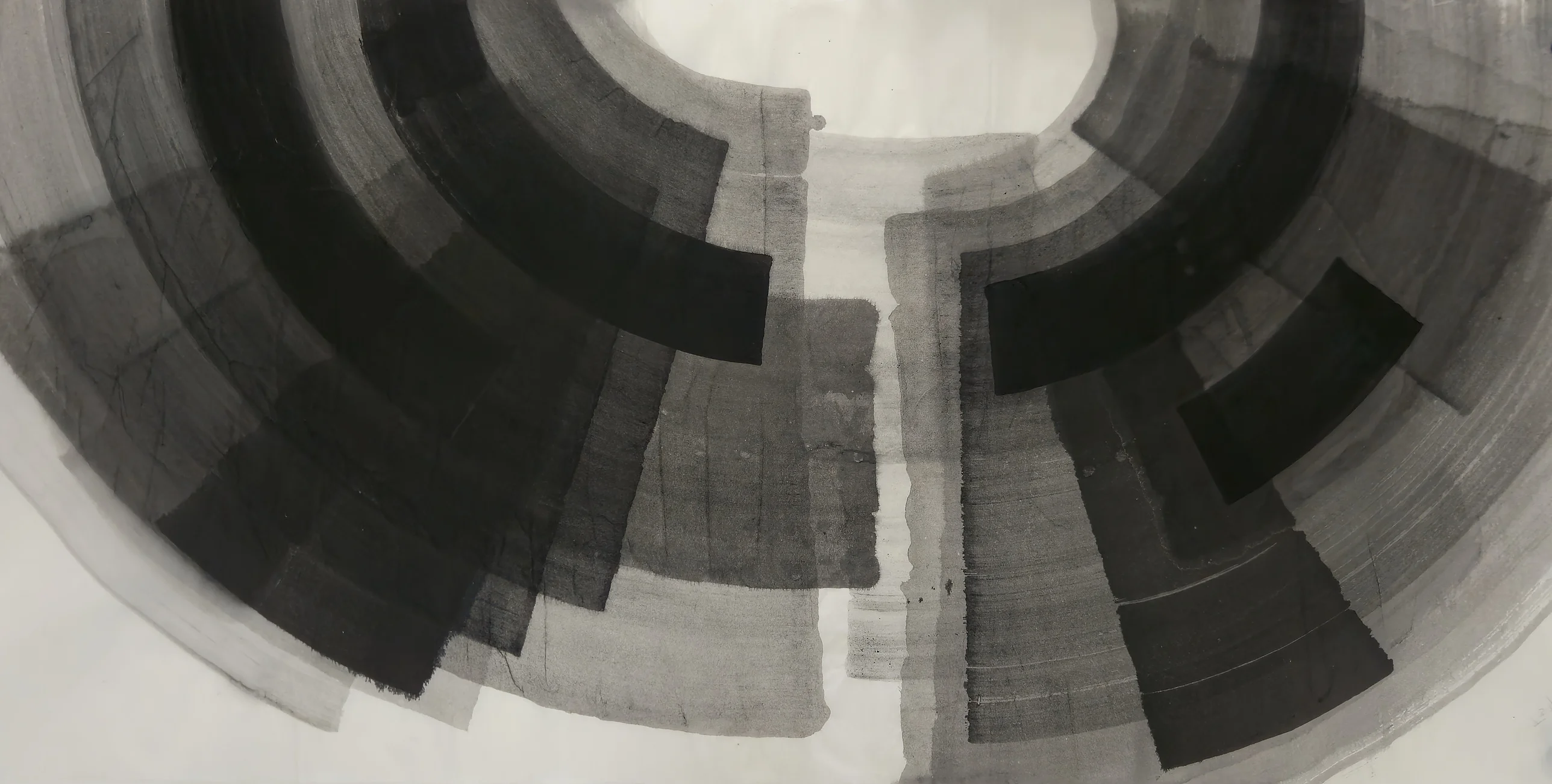 Black and grey concentric arcs form a split arch around a white oval at top, divided by a white channel running down the centre.