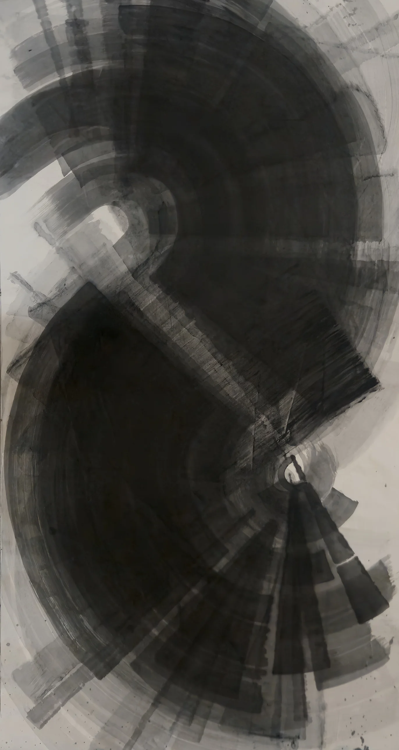 Tall sheet of black and grey ink: two interlocking spirals of curved bands, a small white gap at centre right, a fan of grey wedges below.