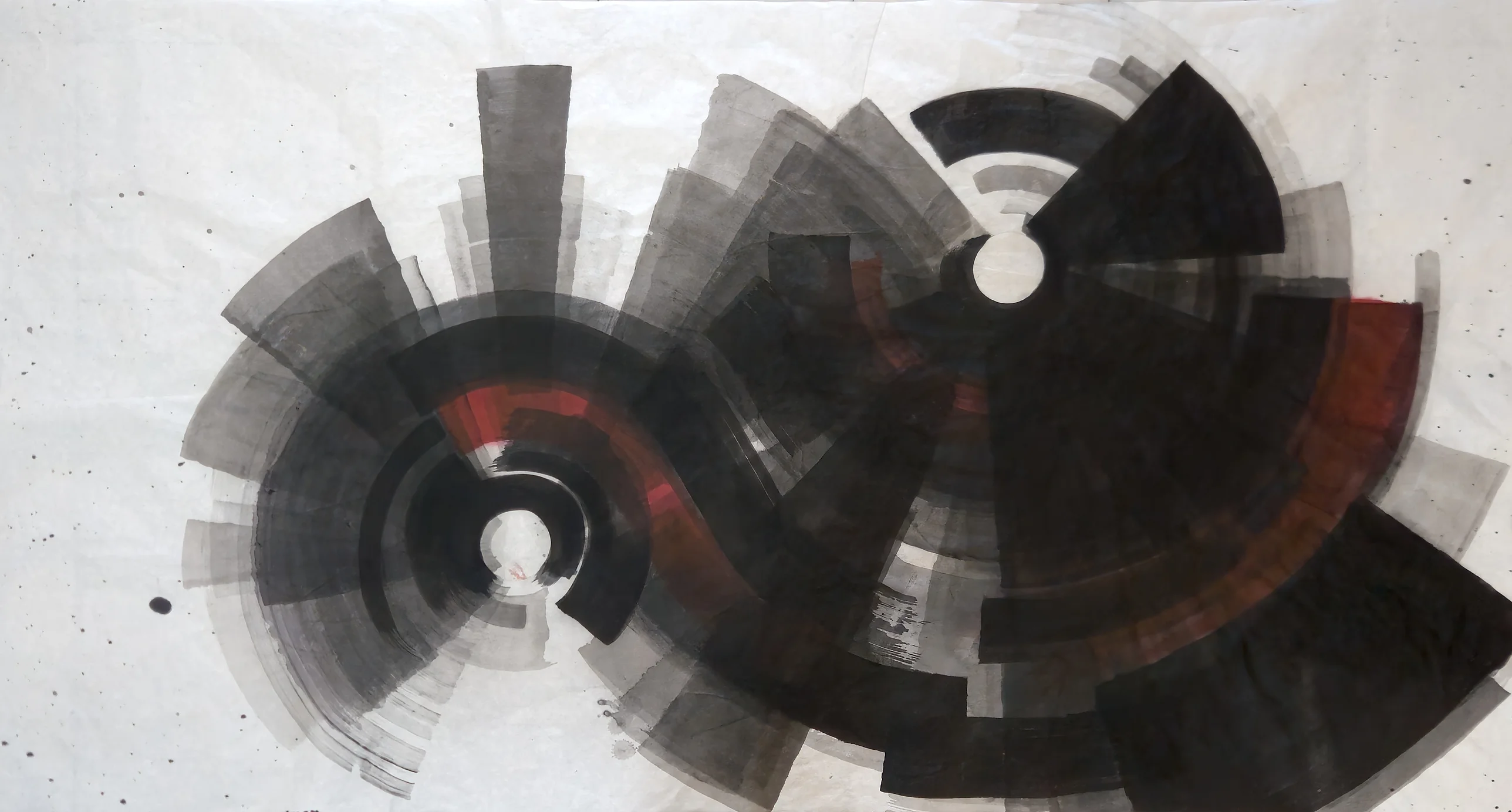 Two large circular ink forms of radiating grey and black blades, joined by a dark curving band with red, heavier toward the right.