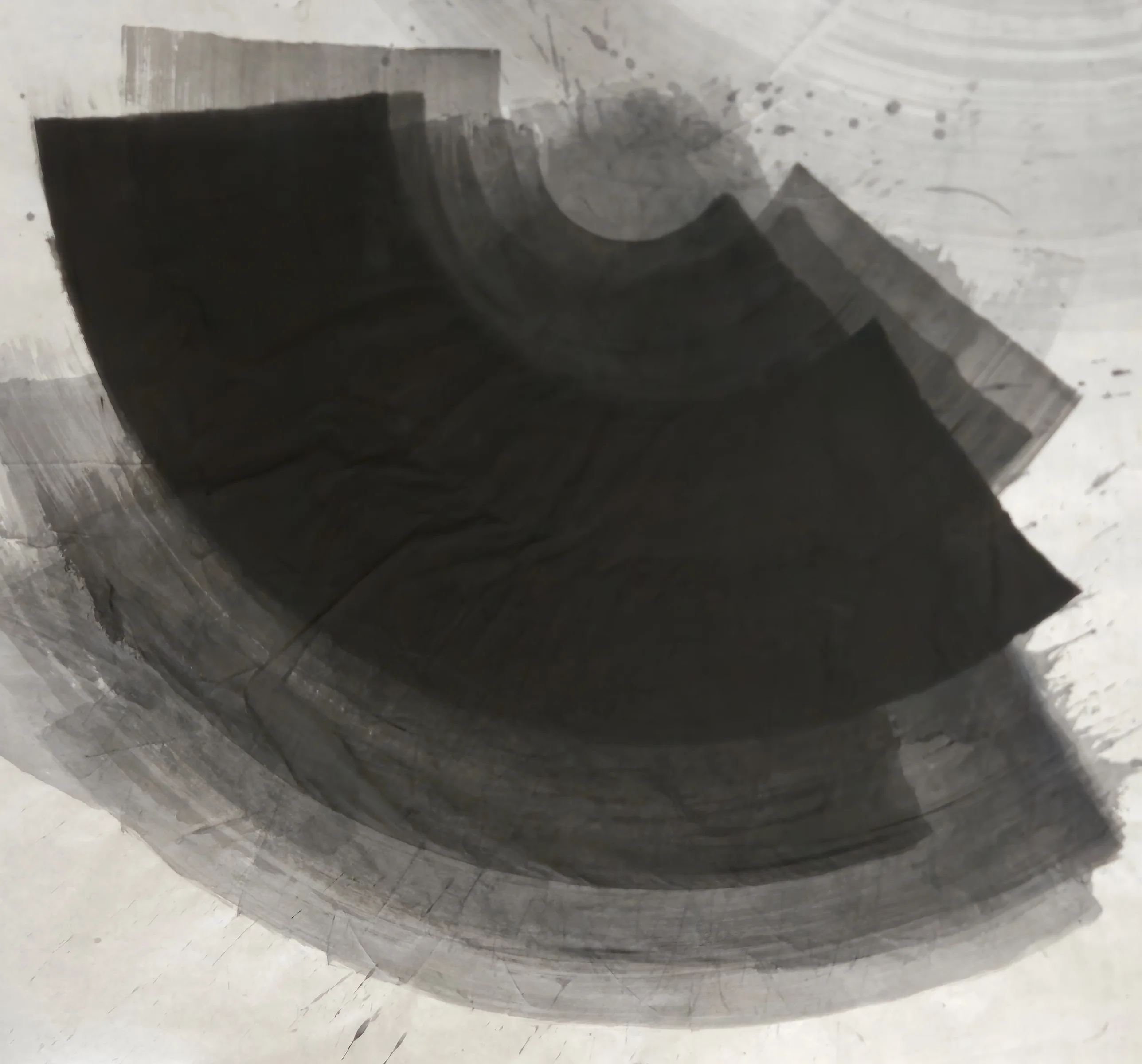 A large black fan shape sweeps from upper left to right over curved grey bands, with spatter and open paper at the top right.