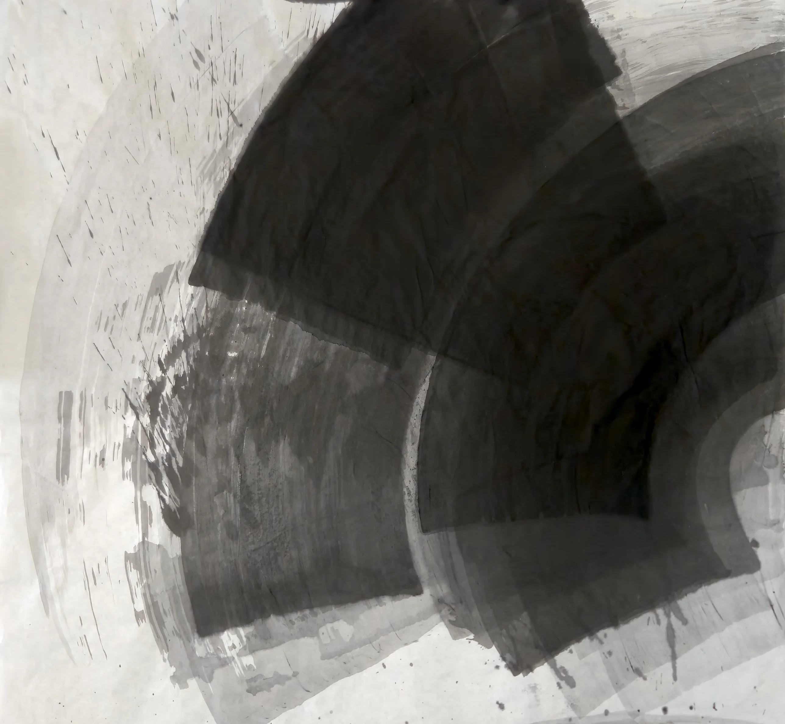 Broad dark and grey arc-shaped bands fan out from the right edge across pale paper, with spatter and faint rings at upper left.