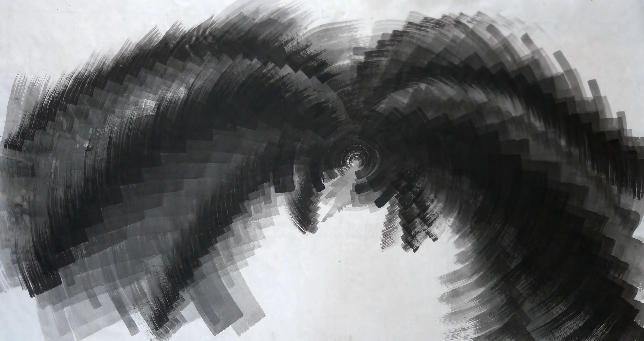 Stepped black and grey brushstrokes spiral from a small centre across wide white paper, darkest at right, with white below centre and in top corners.