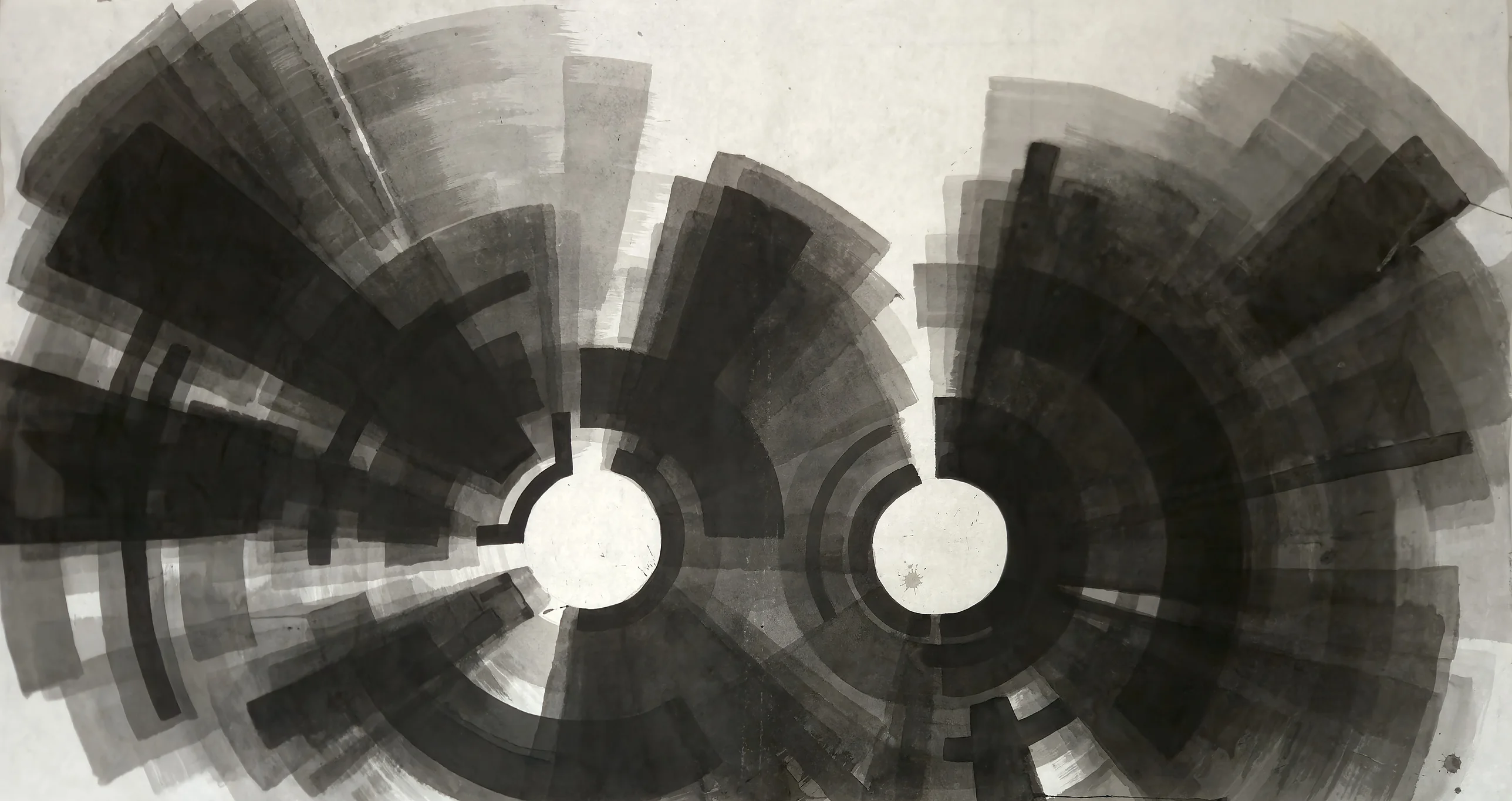 Two white circles near the centre, each ringed by black arcs and radiating grey and black wedges, filling a wide sheet below a pale top.