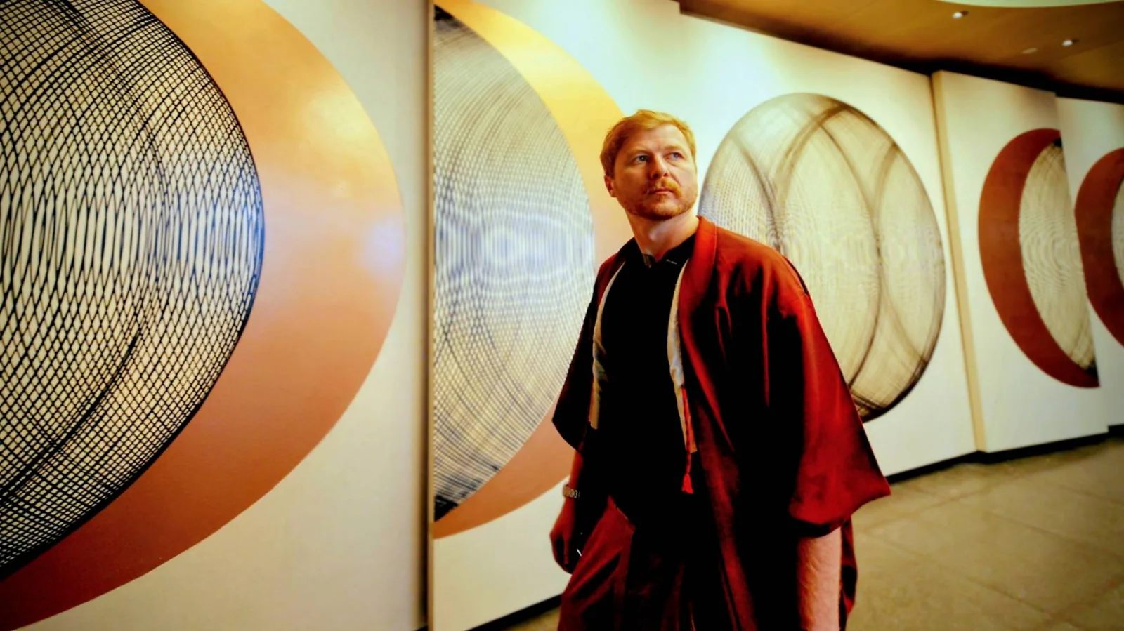 Peter Yuill standing before a wall of his large circular geometric paintings